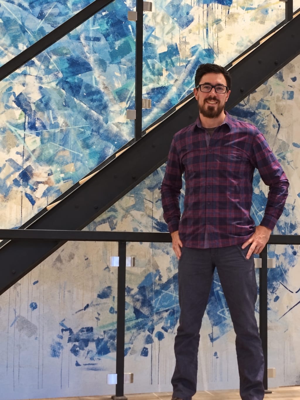 Alexandre St-Amour devant un escalier d'acier et un mur peint, dans un projet livré par ASA.