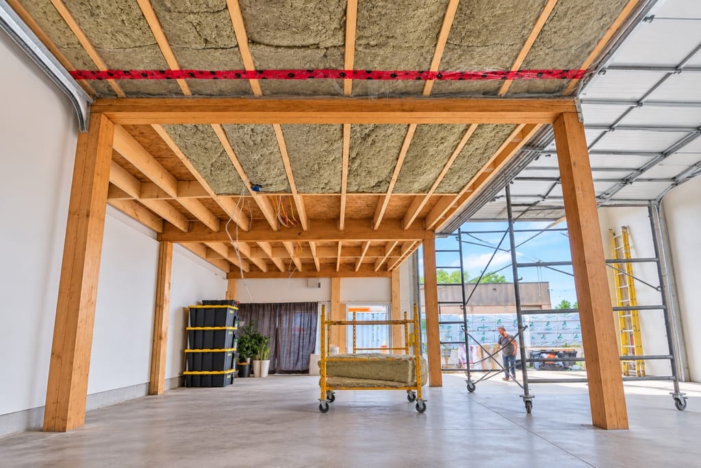Plafond ouvert d'un plex montréalais : les solives et le mur porteur central mis à nu.