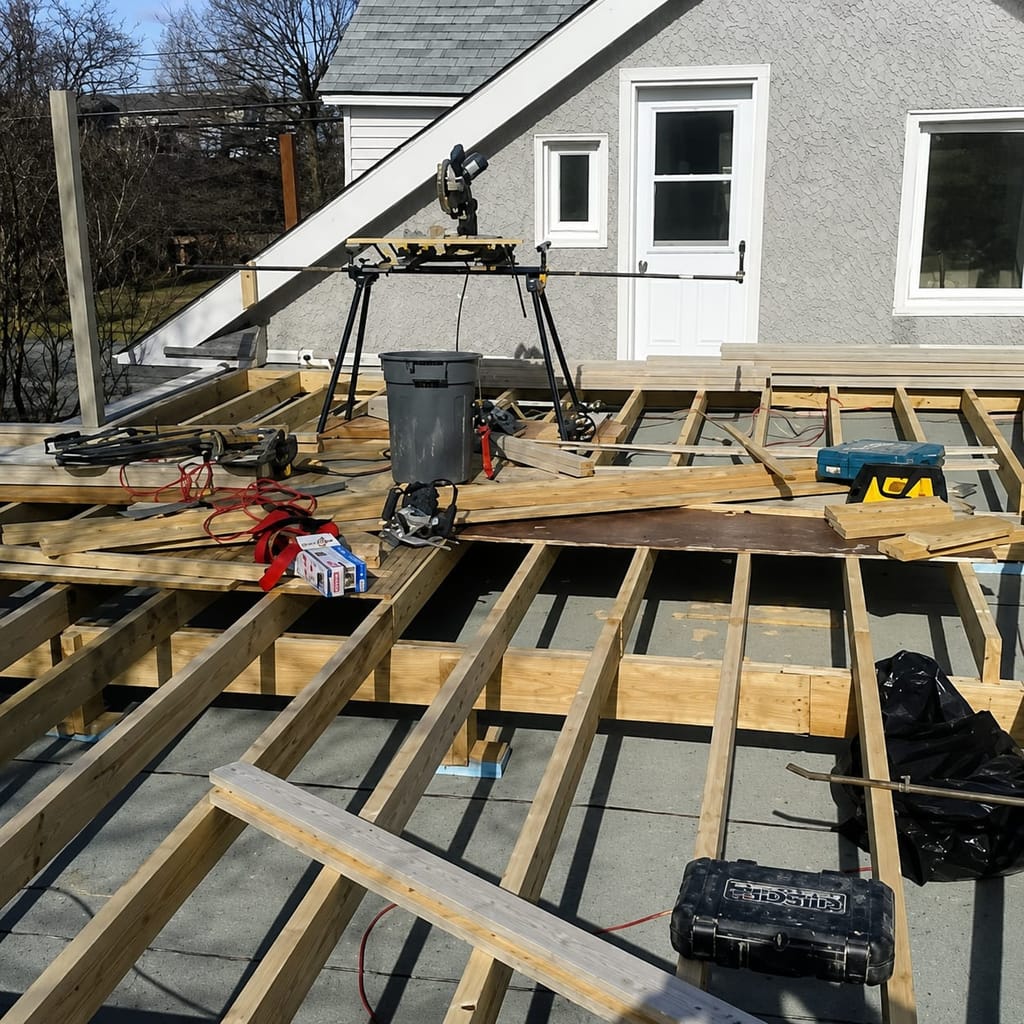 Floor joists of an addition under construction behind a suburban house.